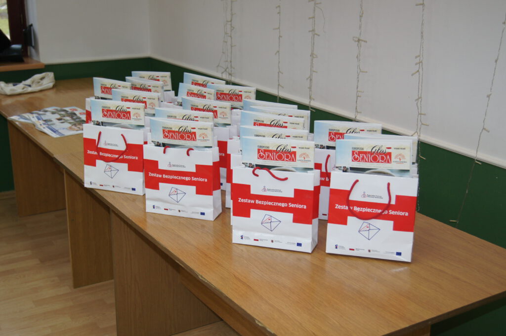 Pakiety upominkowe dla seniorów ustawione na stole, w których są gazety Głos Seniora