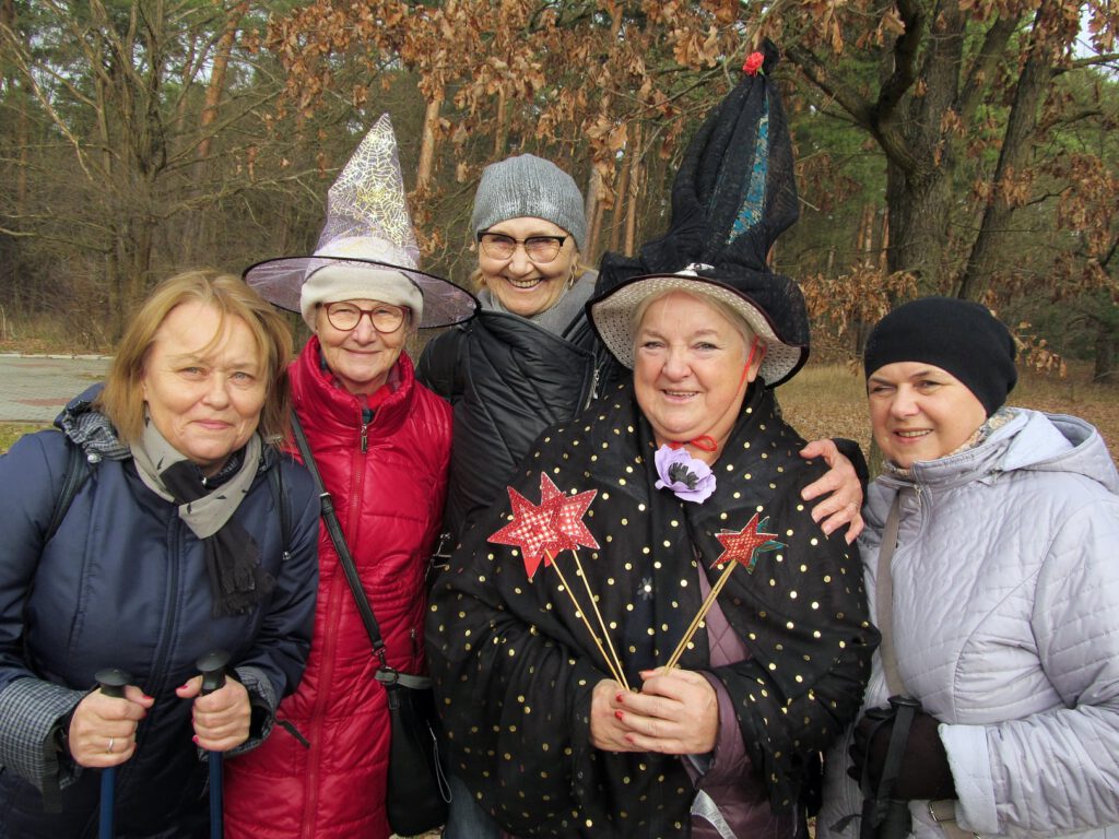 pięć kobiet stoi w plenerze, dwie z nich mają założone kapelusze czarownicy