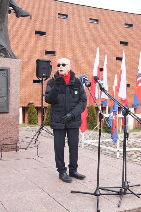 Profesor Janusz Kutta stoi na podwyższeniu przed budynkiem. opowiada o Kazimierzu Wielkim