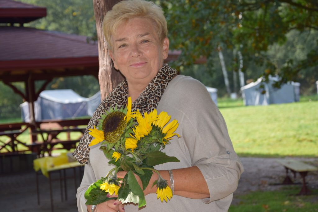 Aleksandra Biegańska stoi w ogrodzie trzymając bukiet kwiatów