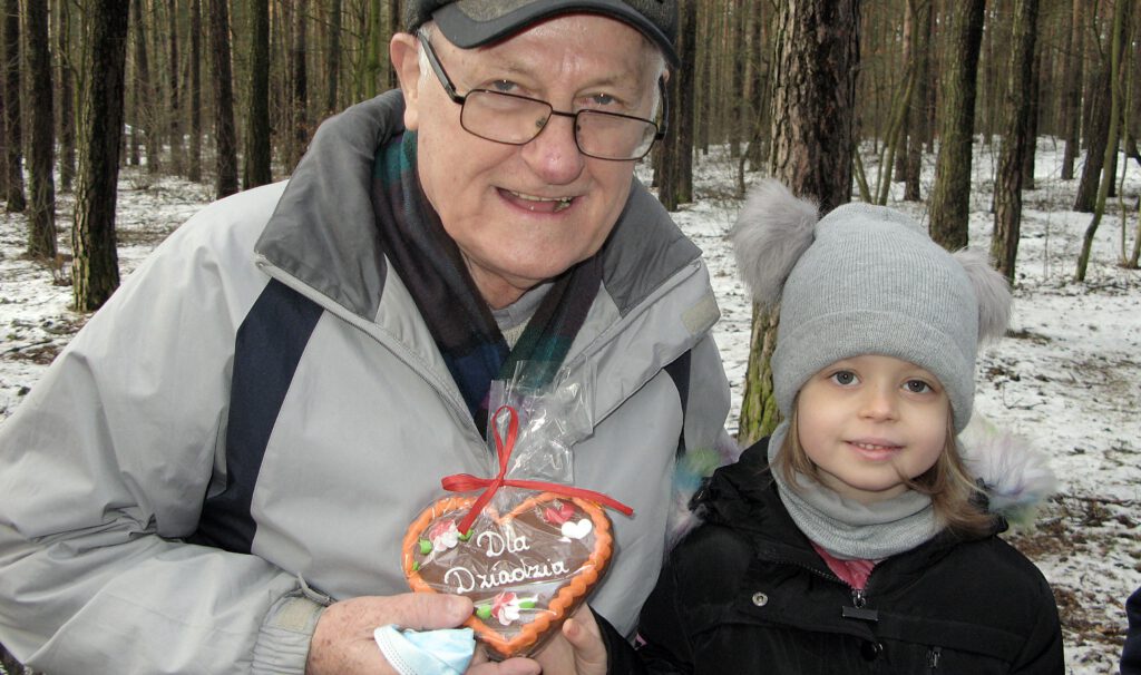 Jan Markiewicz stoi za swoją wnuczką trzymając piernikowe serce