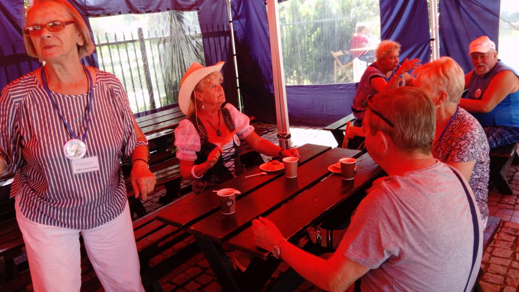 Prudnickie Senioralia, seniorzy rozmawiają i jedzą poczęstunek przy stołach w namiocie