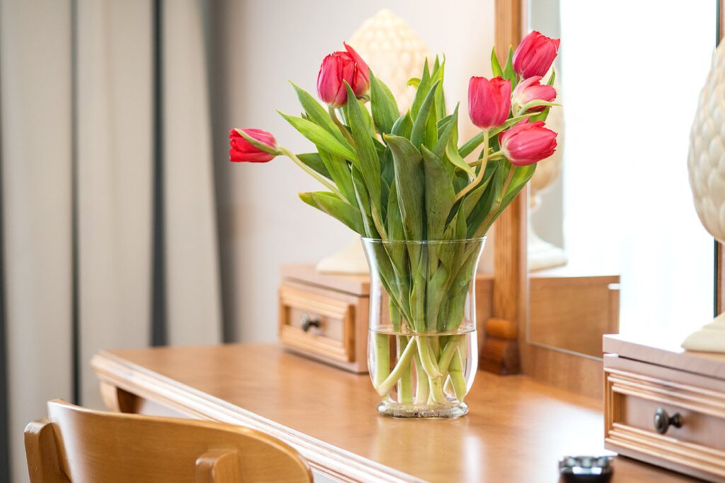 tulipany w szklanym wazonie na stoliku w pokoju